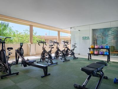 Palestra moderna con cyclette, pesi e finestre panoramiche con vista sul verde.