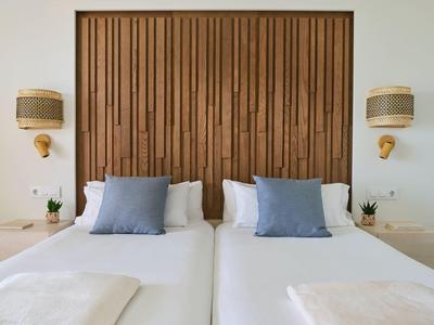 Due letti singoli con cuscini blu e testiera in legno in una camera d'albergo moderna.