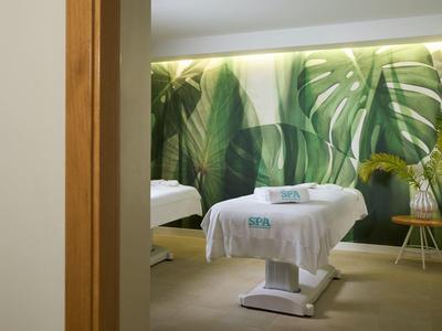 Sala trattamento moderna con lettino e decorazione murale tropicale