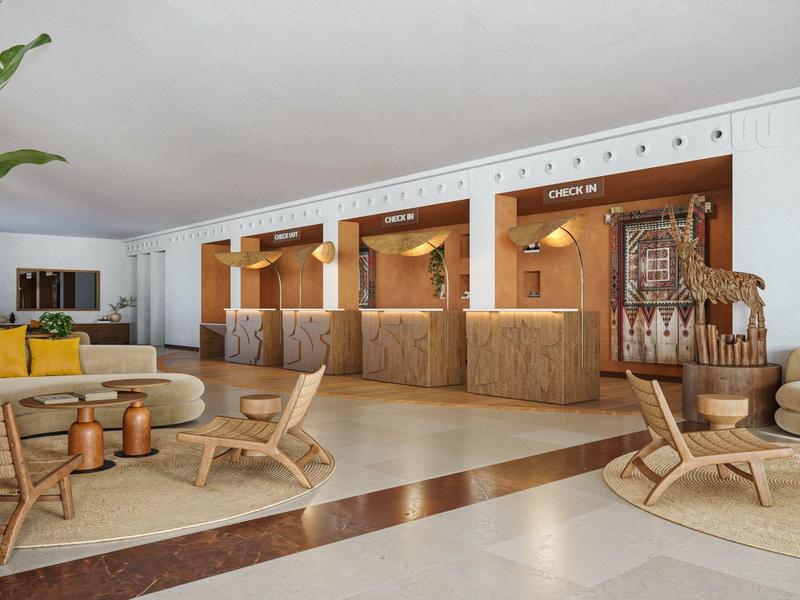 Accogliente reception d'hotel luminosa con banconi in legno, area salotto e piante tropicali dal design moderno.