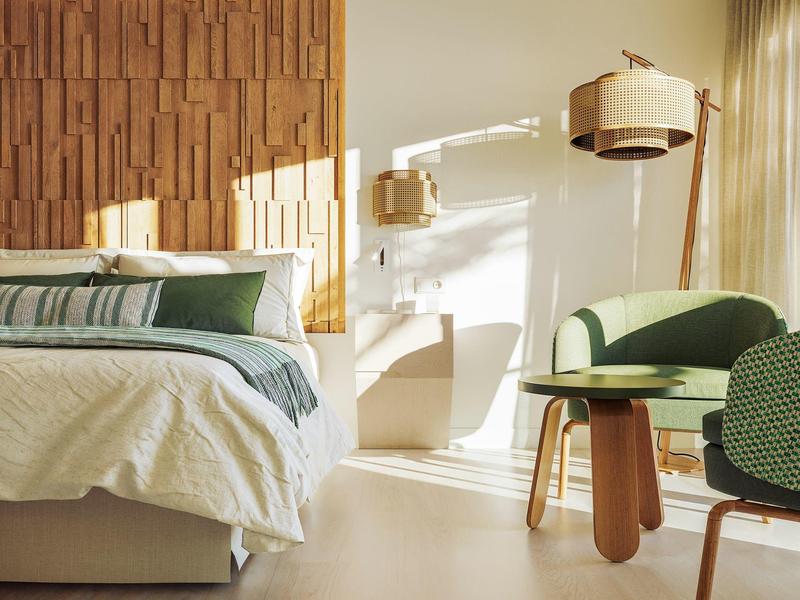 Camera d'hotel luminosa con letto, tavolo rotondo e sedie vicino a una finestra illuminata dal sole.