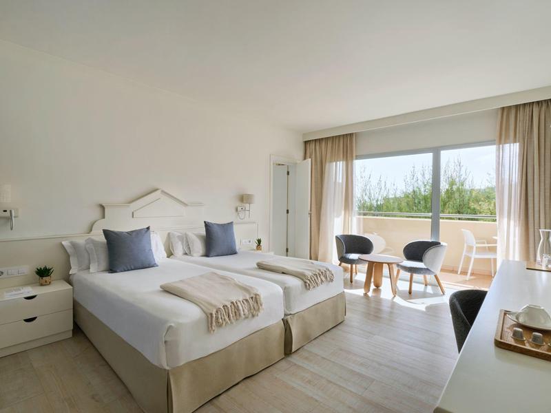 Camera d'hotel moderna con due letti singoli, balcone e tende chiare