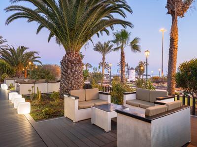 Terrasse d'hôtel avec palmiers et sièges modernes au crépuscule.