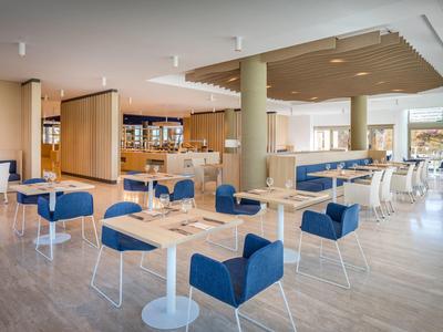 Salle de restaurant moderne avec chaises bleues et lumière naturelle abondante.