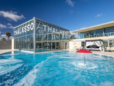 Piscine extérieure avec toboggans et bâtiment moderne sous ciel bleu.