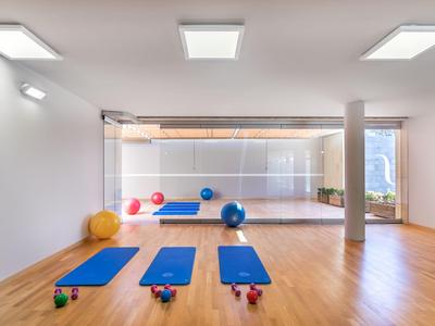 Heller Fitnessraum mit Holzboden, drei blauen Yogamatten und Hanteln vor großem Spiegel.