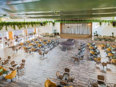 Großer, heller Hotelkonferenzraum mit vielen Sitzplätzen und Bühnenbereich.