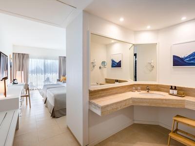 Chambre d'hôtel lumineuse avec salle de bain attenante équipée d'un grand miroir.