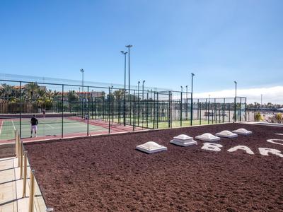 Sportanlage mit Tennisplätzen und Sitzgelegenheiten unter blauem Himmel