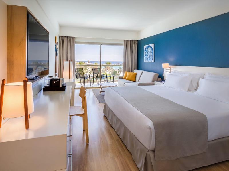 Chambre d'hôtel lumineuse avec lit double, balcon et décoration moderne.