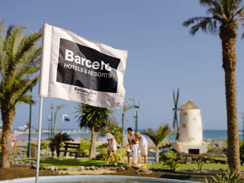 Drapeau Barcelo dans un jardin tropical avec éolienne et vue mer en arrière-plan.