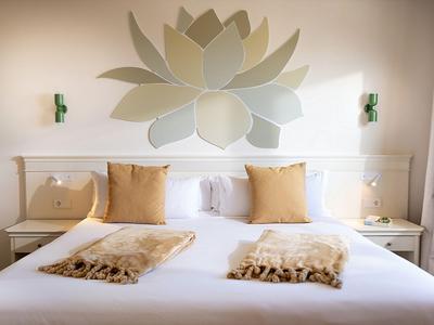 Pokój hotelowy z dużym łóżkiem, dwoma poduszkami, miękkimi kocami i dekoracją ścienną lotosu.