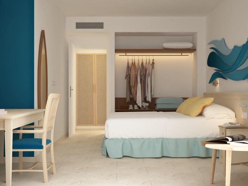 Nowoczesny pokój hotelowy z podwójnym łóżkiem, biurkiem i krzesłem w jasnych kolorach.