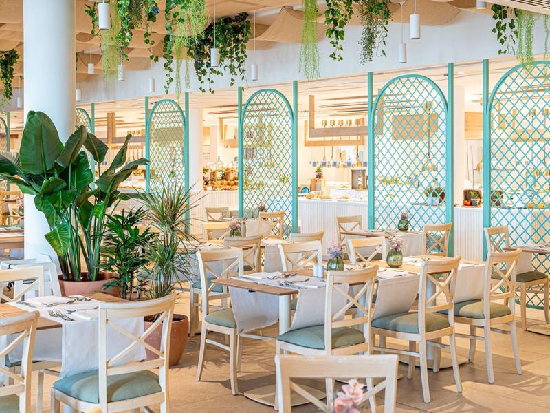 Jasne, nowoczesne wnętrze restauracji z roślinami i drewnianymi meblami.