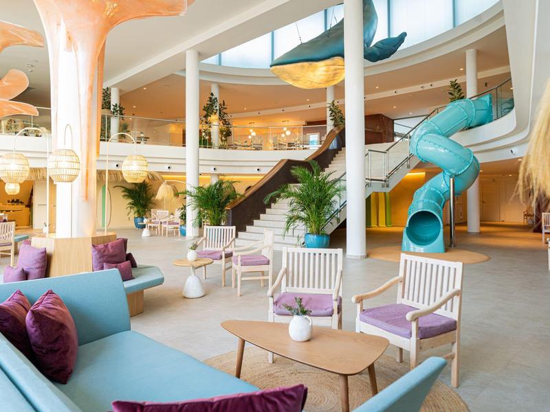 Nowoczesny hol hotelowy z kolorowymi siedzeniami i niebieską zjeżdżalnią