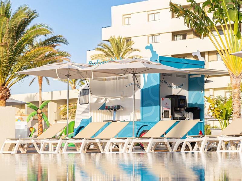 Leżaki i parasole przy basenie przed budynkiem hotelu pod czystym niebem