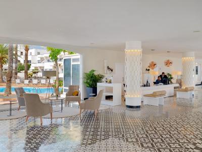 Heller, moderner Empfangsbereich mit gemustertem Boden, Sitzmöbeln und Blick zum Pool draußen.