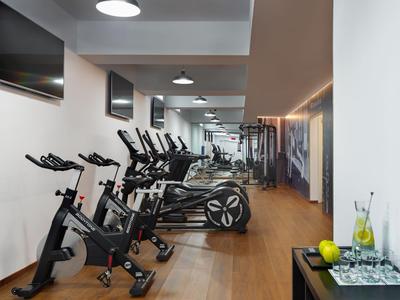 Modern gym with bikes, treadmills, and wood flooring in a hotel setting.