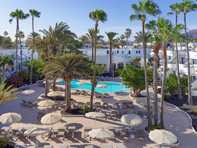 Hotel pool with sun loungers and palm trees in a tropical setting.