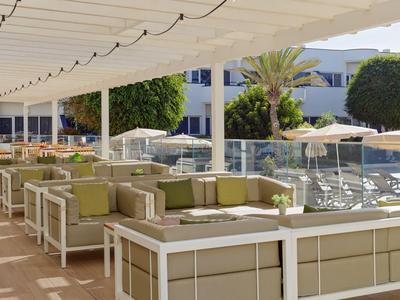 Enclosed outdoor area with comfortable seating and sun umbrellas in a warm, bright setting.