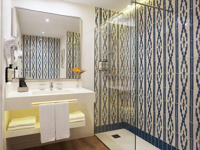 Modern bathroom with shower, sink, and mirror, featuring white and blue patterned walls.