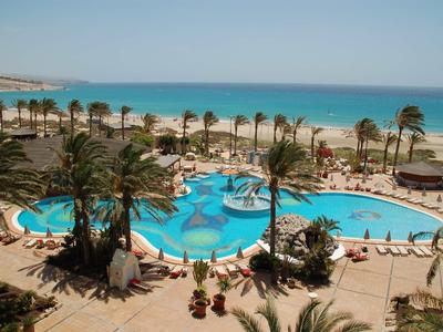 Grande piscina con palme vicino al mare in una località turistica tropicale.