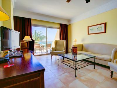 Soggiorno luminoso con divano, poltrone e vista sul balcone con palme