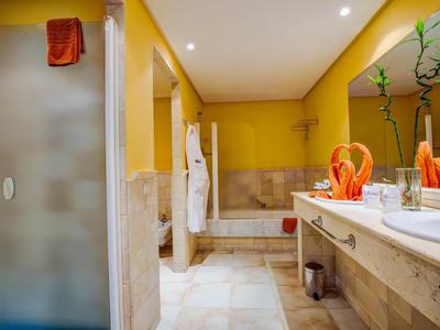 Bagno moderno con pareti gialle, doccia, vasca da bagno e due lavandini.