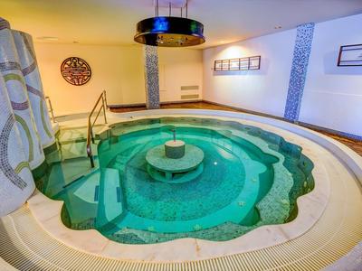 Una piscina interna circolare con bordi a gradini e una piccola fontana al centro.