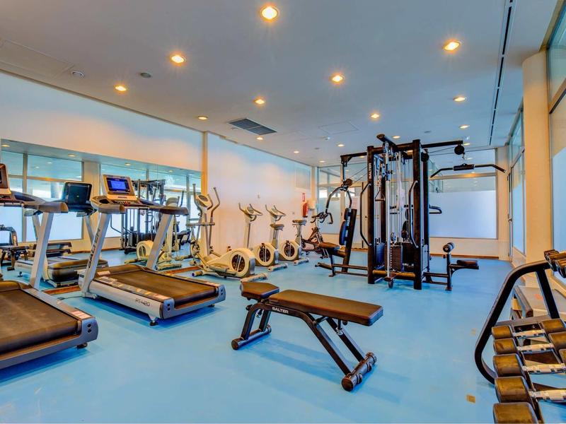 Palestra luminosa con tapis roulant, cyclette, attrezzi per pesi e manubri.