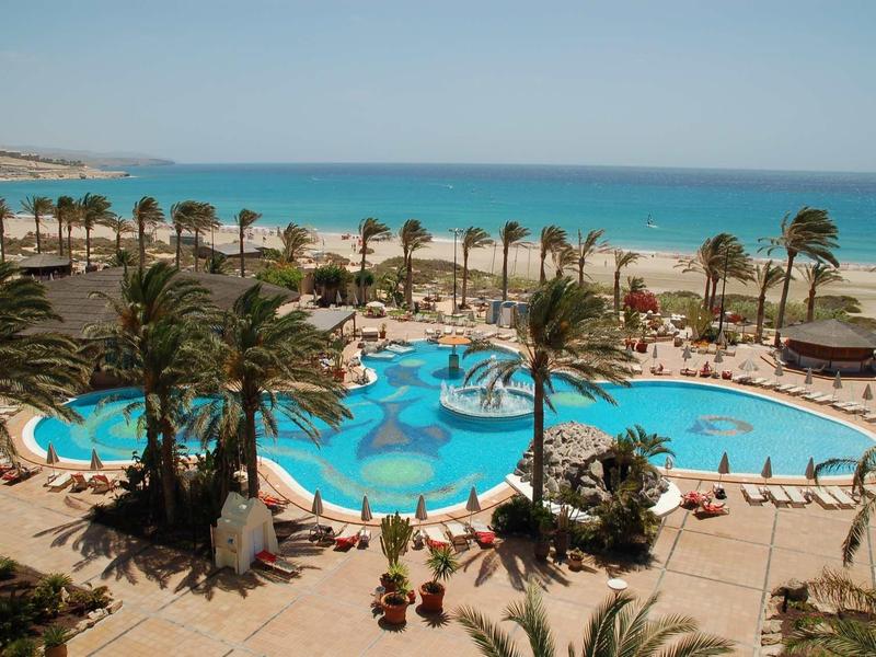 Grande piscina con palme vicino al mare in una località turistica tropicale.