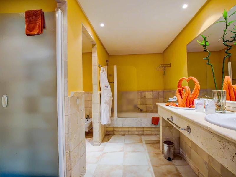 Bagno moderno con pareti gialle, doccia, vasca da bagno e due lavandini.