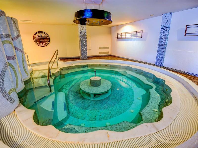 Una piscina interna circolare con bordi a gradini e una piccola fontana al centro.