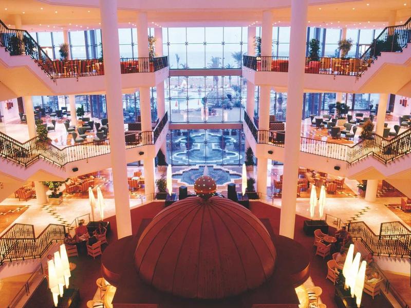 Hotel con piscina illuminata e palme di notte sotto un cielo stellato