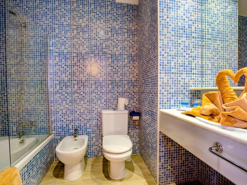 Koupelna s toaletou, bidetem, vanou a umyvadlem s pečlivě složenými ručníky.