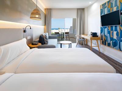 Chambre d'hôtel moderne avec deux lits, bureau, balcon et décoration murale colorée.