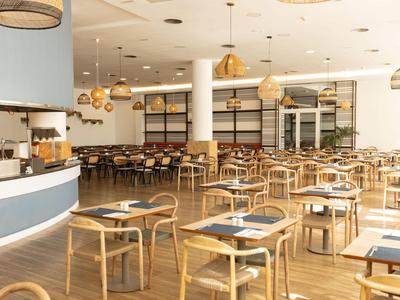 Salle à manger claire avec mobilier en bois et suspensions dans un hôtel.