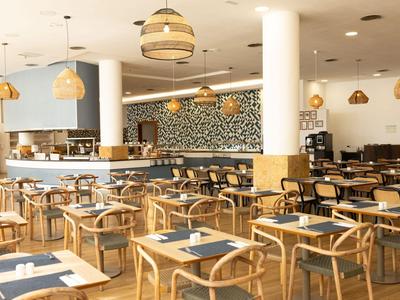 Salle à manger d'hôtel moderne avec chaises en bois et grandes lanternes suspendues.