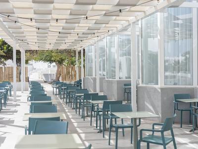 Terrasse extérieure avec sièges bleus modernes et pergola blanche.