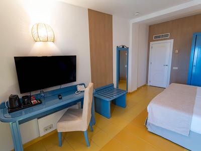 Modern hotel room with blue desk, TV, and yellow flooring.