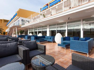Modern outdoor terrace with comfortable armchairs and blue lounge furniture in front of a hotel.