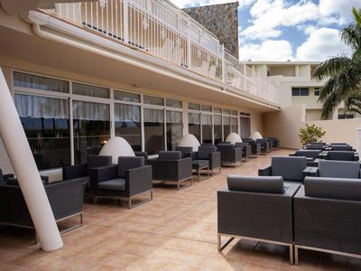 Outdoor hotel terrace with black seating groups and white umbrellas.