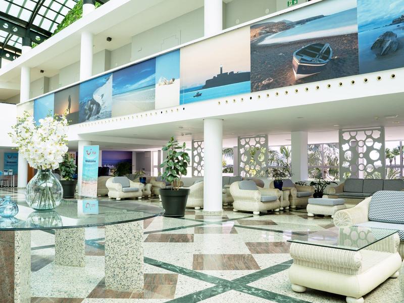 Světlá hotelová hala s moderním nábytkem a velkými obrazy na stěně