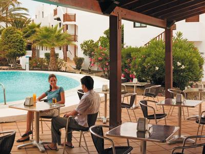 Zewnętrzny kącik kawowy przy basenie z gośćmi i otoczeniem basenu w hotelu.