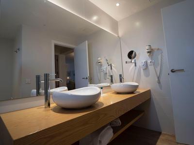 Modernes Badezimmer mit doppeltem Waschbecken auf Holzablage und großem Wandspiegel.