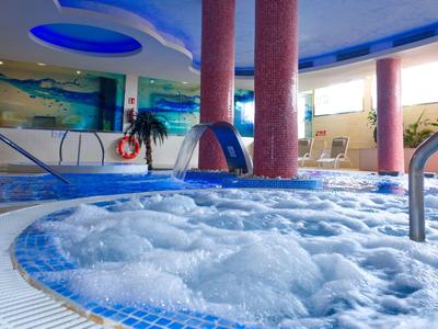 Hell beleuchteter Whirlpool mit sprudelndem Wasser in modernem Spa-Bereich mit blauen Akzenten.