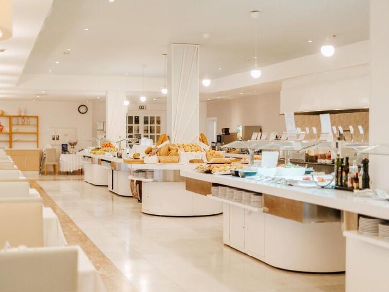 Ampia zona buffet con varie opzioni di cibo in una sala da pranzo moderna e luminosa.