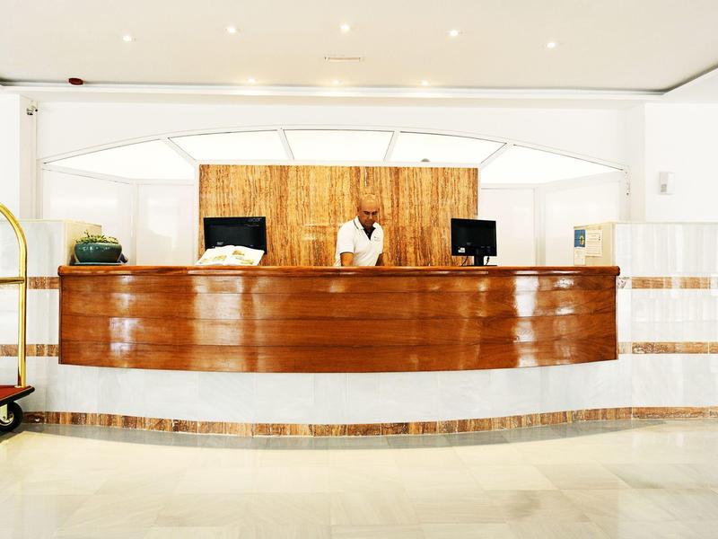 Banco reception dell'hotel con personale dietro in un lobby spaziosa e luminosa.