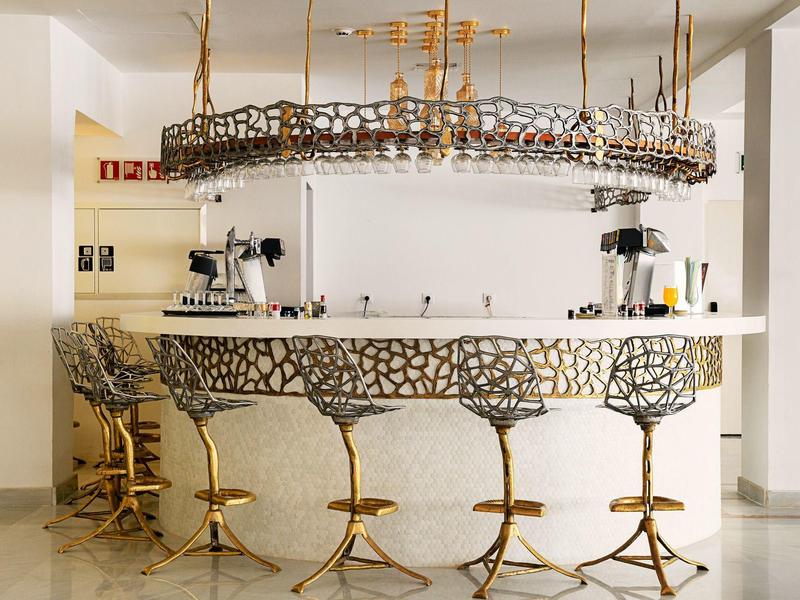 Bar circolare moderno in hotel con sgabelli dorati unici e portabicchieri sospeso.