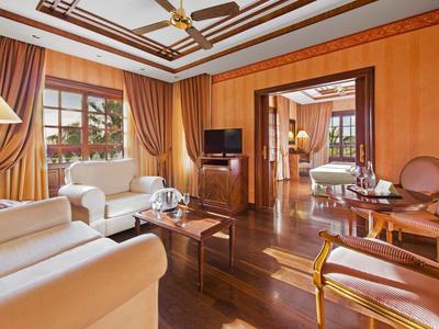 Elegantní obývací pokoj s posezením, velkým oknem a dřevěnými podlahami v hotelovém pokoji.